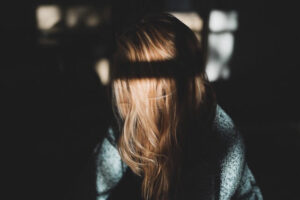 Trauriges Mädchen im Schatten mit braunen Haaren.