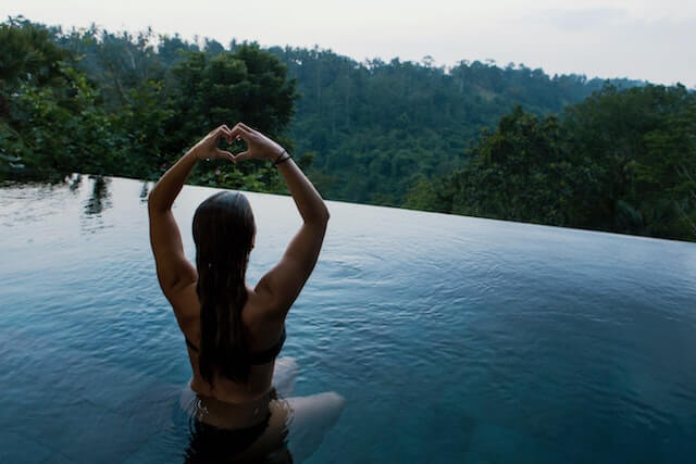 Junge attraktive Dame praktiziert Yoga in einem Pool in Bali. 