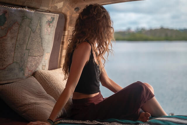 Junge alternative Frau mit Locken in der Natur am See